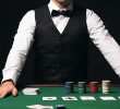 A male croupier at a Texas Hold'em poker table.