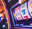 A row of modern slot machines in a casino, with colorful displays and buttons.