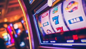 A row of modern slot machines in a casino, with colorful displays and buttons.