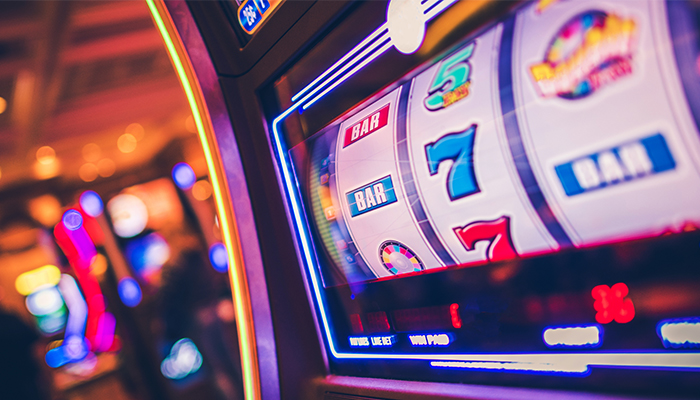 A row of modern slot machines in a casino, with colorful displays and buttons.