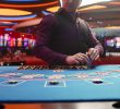 A dealer managing a card game at a table with cards and chips.