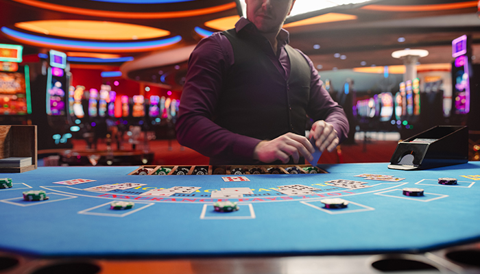 A dealer managing a card game at a table with cards and chips.